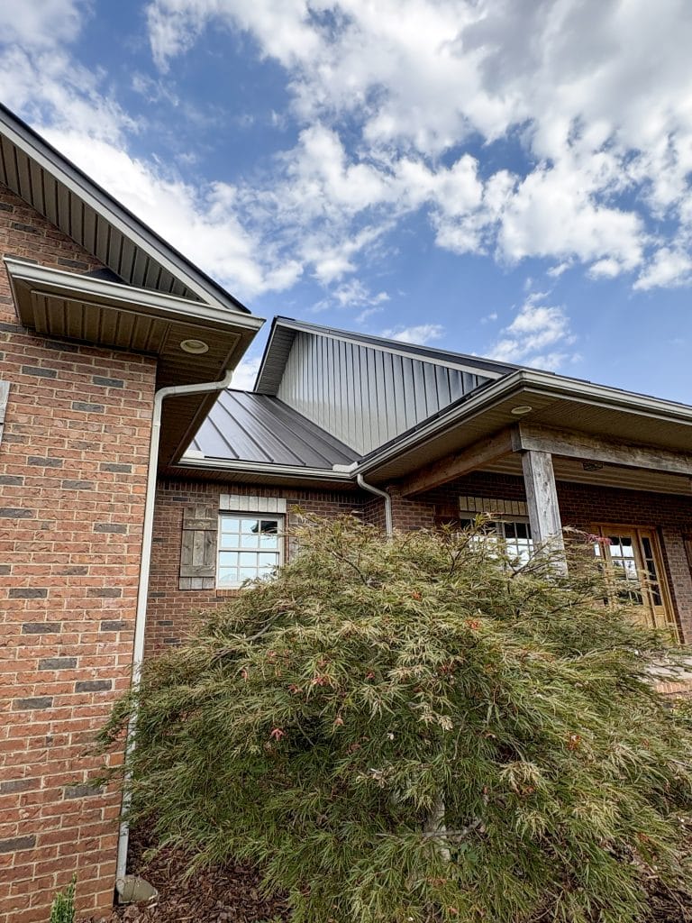 Low-angle image showing the undamaged landscaping in the foreground, and the brand-new roof in the background.
